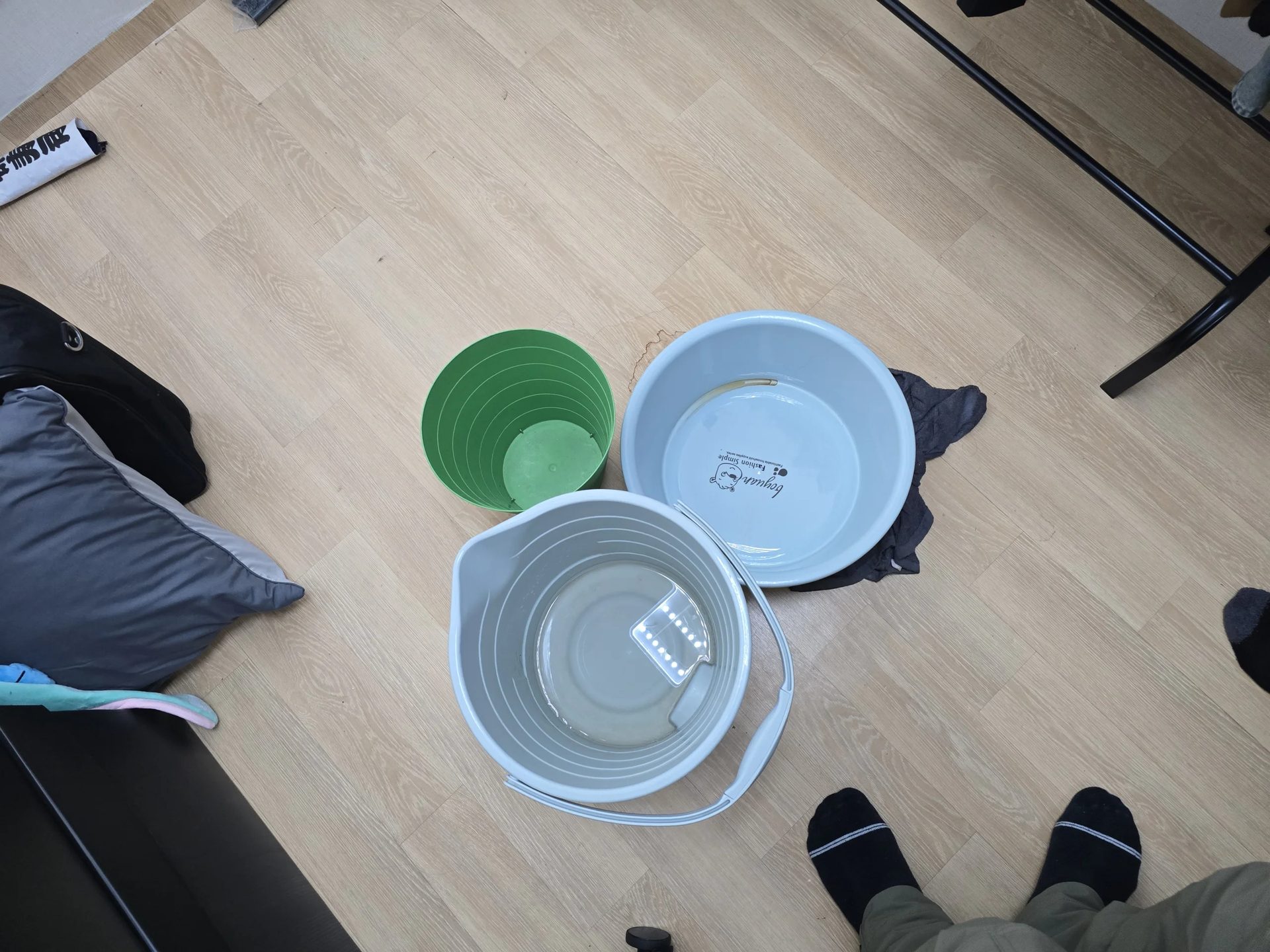 누수가 발생한 실내 바닥에 세숫대야와 양동이를 놓아 떨어지는 물을 받아 둔 모습